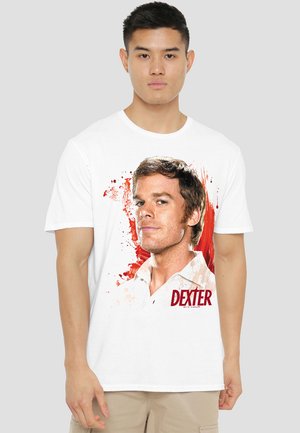 White cotton t-shirt featuring a graphic print of a man with short brown hair against a red splatter backdrop, with "DEXTER" printed below.