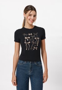 Schwarzes T-Shirt aus Baumwolle, mit einem zentralen Design aus verschiedenen Schleifen in einem glänzenden, metallischen Roségold, kurzen Ärmeln und einer taillierten Passform.