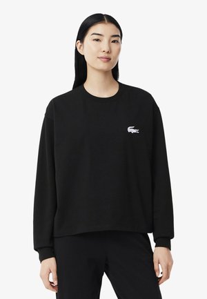 Zwarte katoen sweatshirt met lange mouwen, ronde hals en een wit geborduurd logo op de linkerborst. Zachte textuur en losse pasvorm.