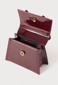 Sac à main bordeaux breveté avec une finition brillante, doté d'une fermeture à pression dorée et d'un intérieur noir, conçu avec un agencement en deux compartiments.