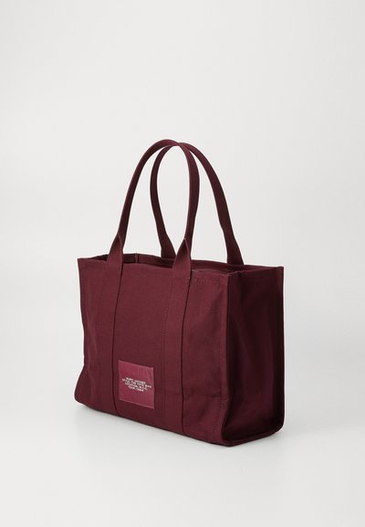 Borsa tote rettangolare bordeaux con doppio manico e etichetta cucita sul lato anteriore.