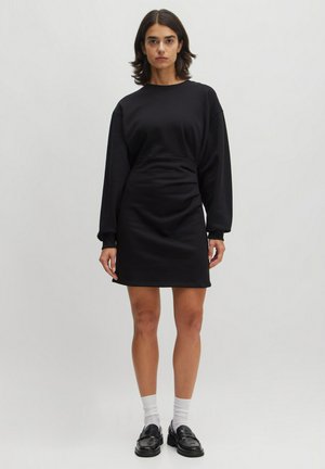 Zwarte sweatshirtjurk van zacht stof, met lange mouwen, een relaxte pasvorm en een zoom die halverwege de dij valt. Eenvoudig ontwerp zonder patronen.
