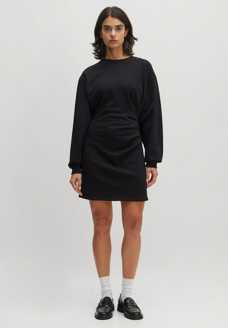 Schwarzes Sweatshirtkleid aus weichem Stoff, mit langen Ärmeln, lässiger Passform und einem Saum, der bis zur Mitte des Oberschenkels reicht. Einfaches Design ohne Muster.