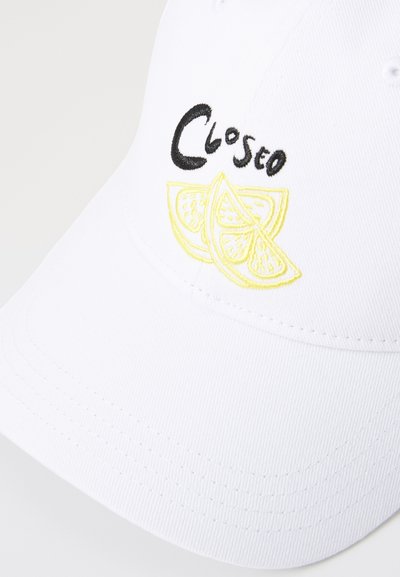Vit basebollkeps med "Closeo" i svart brodyr och gula citronskivor, textil med struktur och en böjd skärm.