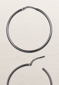 Schwarzes Metall-Accessoire in Form eines Rings mit glatter Oberfläche und einem Scharnierelement. Verfügt über einen kleinen gebogenen Abschnitt vom Hauptring.