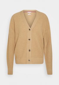 Vaaleanbeige neulejakku, jossa on V-pääntie ja viisi nappia edessä. Hihoissa ja helmassa on ribattu rakenne. Teksturoidusta kankaasta tulee lämpöä.