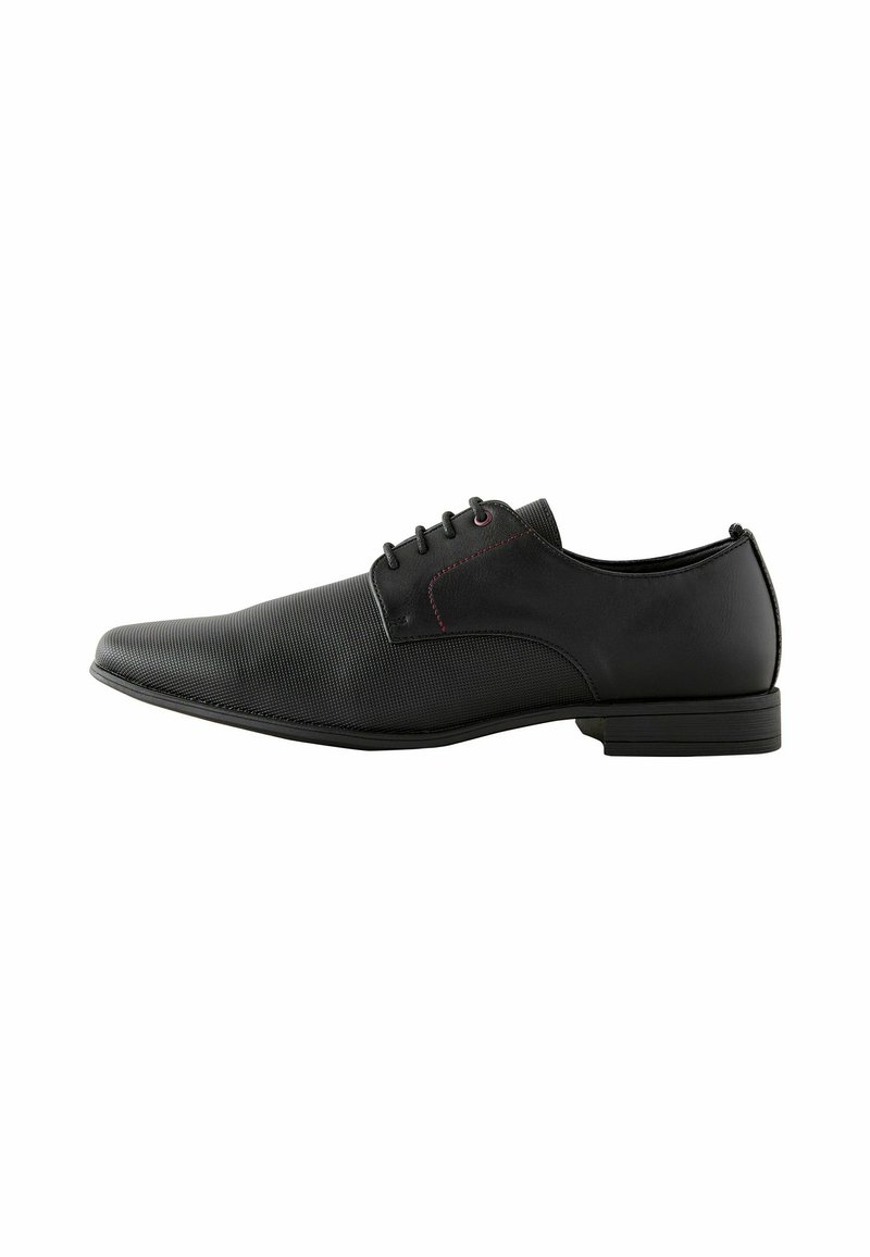 Zwarte veterschoenen met een bovenwerk van gladleer en een textuurpaneel. Beschikt over een slank ontwerp, platte zool en subtiele rode stikselaccenten.