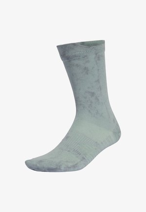 Chaussette en coton vert clair avec une bordure côtelée et une texture lisse, présentant un motif légèrement marbré ainsi qu'un renfort à la pointe et au talon.