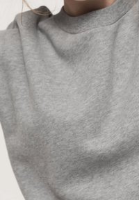 Grå sweatshirt med rund halsringning, mjuk textur och lätt drapering. Tyget har en slät, odekorerad finish.