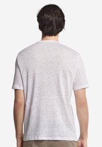 Vit t-shirt med kort ärm, tillverkad av lätt, något texturerad tyg. Har en rundad halsringning och en avslappnad, ledig passform.