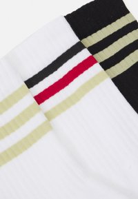 Calcetines de algodón con textura acanalada en blanco, negro y oliva, además de una franja roja audaz para contraste.