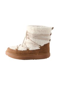 Botte en daim beige et fausse fourrure crème avec lacets, semelle en caoutchouc et détails en métal doré ; surface texturée sur toute la botte.