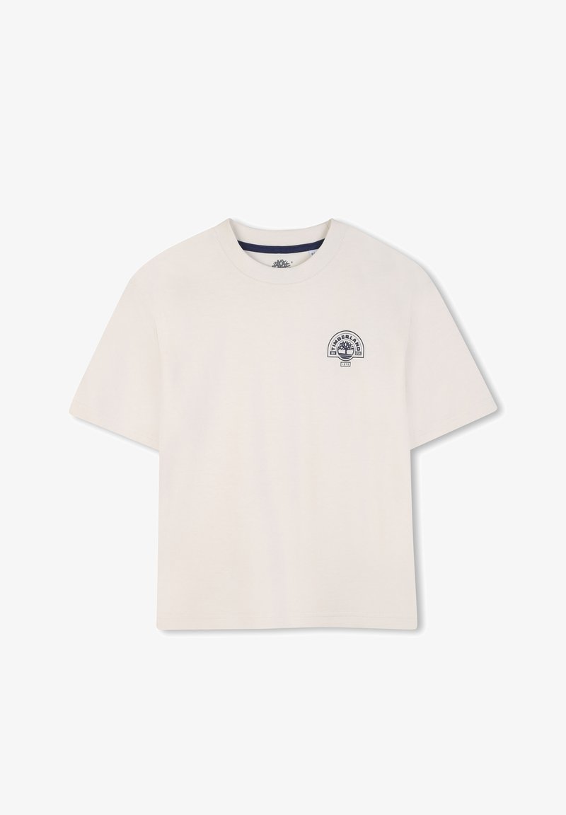T-shirt en coton beige clair avec un col rond. Présente un petit logo graphique bleu marine sur la poitrine gauche. Manches courtes, coupe décontractée.