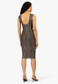 Bodycon jurk in een donker metallic stof. Heeft een diepe rug uitsnijding, ritssluiting en zijaccenten met knopen. Soepele textuur en een op maat gemaakte pasvorm.