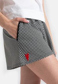 Czarno-białe spodenki w kratę z kieszeniami i naszywką w kształcie czerwonego serca. Wykonane z lekkiej tkaniny, z elastyczną talią.