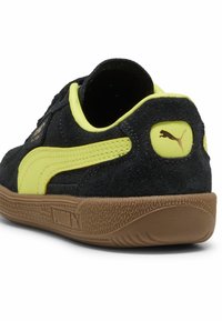 Zwarte suedine sneakers met felgele accenten, met een klassiek ontwerp, een gestructureerde rubberen zool en het Puma-logo op de hiel.