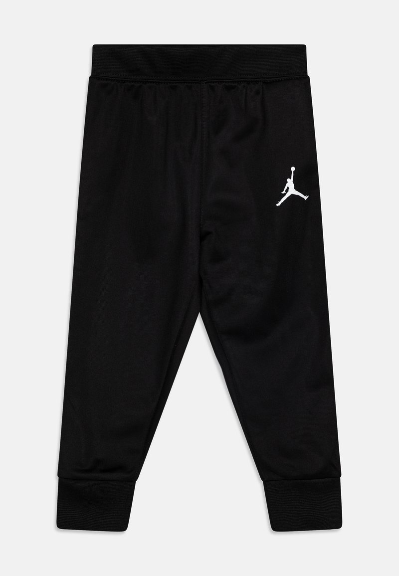 Pantalones deportivos negros con cintura y puños elásticos, con un logo Jumpman blanco en la parte superior de la pierna izquierda.
