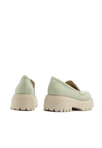 Zielone skórzane półbuty wsuwane z masywną beżową podeszwą, zaokrąglonym noskiem i niskim obcasem. Teksturowana cholewka z przeszyciami po bokach.