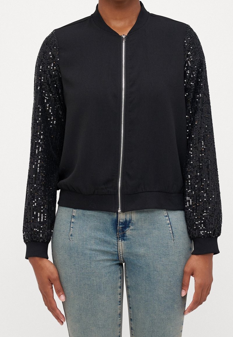 Czarna kurtka bomberka z jednolitym korpusem z tkaniny i rękawami ozdobionymi cekinami. Posiada przedni zamek błyskawiczny, ściągacze na mankietach oraz teksturowane akcenty.
