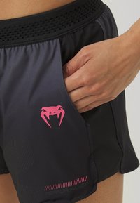 Schwarze Sportshorts mit einem strukturierten Bund, pinkem Logo mit einer Schlange und einer Seitentasche für zusätzlichen Komfort. Leichtes, atmungsaktives Material.