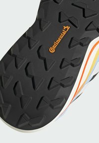 Zwarte rubberen zool met een profielpatroon van diamant- en driehoekige vormen. "Continental" logo in oranje nabij de middenzool.