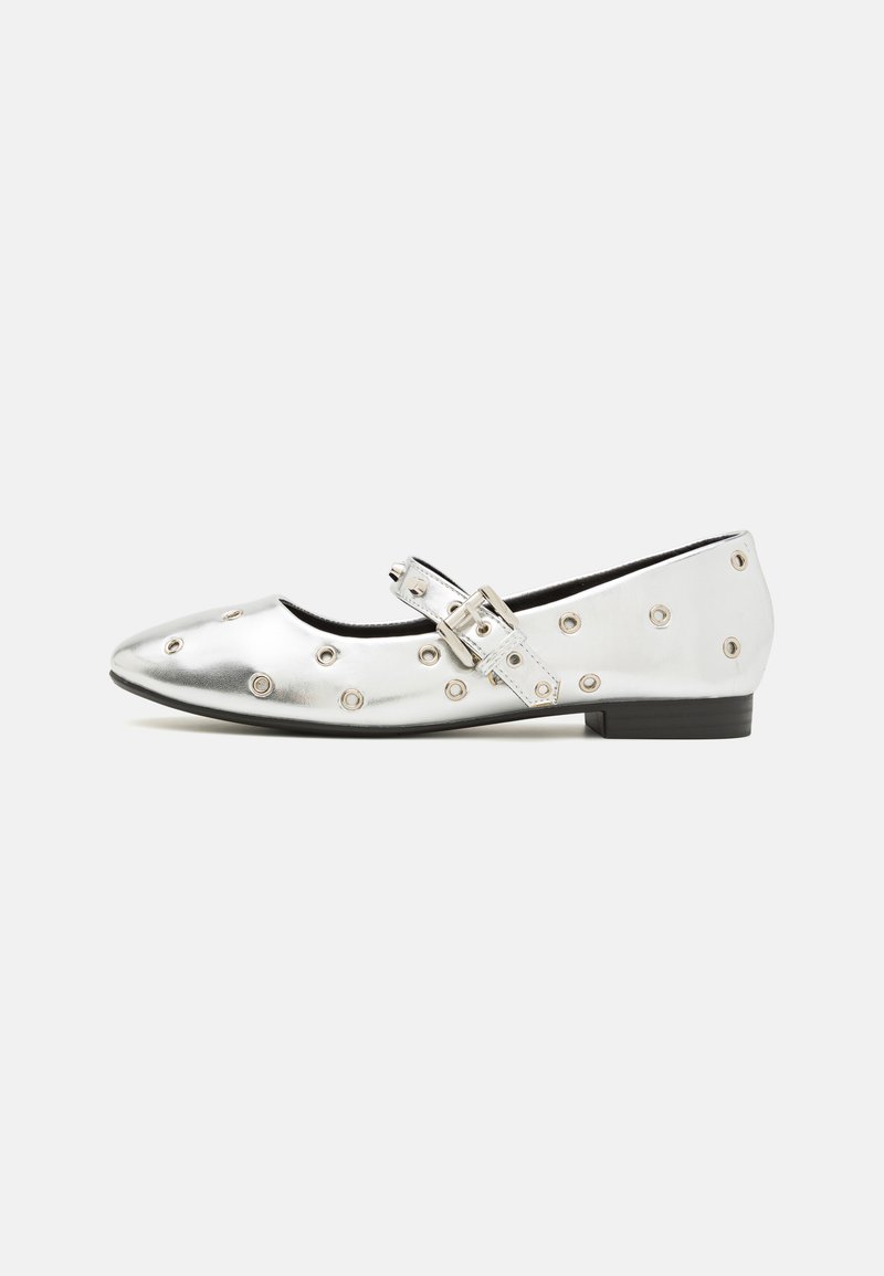 Ballerines métalliques argentées avec un bout rond, présentant une sangle à boucle et des clous circulaires décoratifs sur le côté. Talon bas noir.