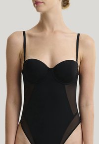 Schwarzer Body aus glattem Stoff mit transparenten Netzseitenteilen, ausgestattet mit einer strukturierten, gepolsterten Brust und dünnen, verstellbaren Trägern.