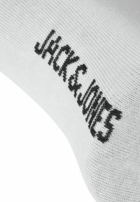 Tissu blanc avec "Jack & Jones" tricoté en fil noir en orientation diagonale.