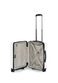 Valigia rigida da cabina, esterno bianco, dettagli neri, manico retrattile, quattro ruote, interno beige con cinghie incrociate elastiche e tasca con zip.