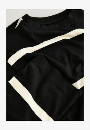 Sort bomulds-T-shirt med hvide diagonale striber på fronten og ærmet. Blød tekstur, rund halsudskæring og standard pasform.