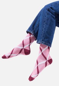 Różowo-bordowe skarpetki w wzór argyle z geometrycznym motywem, wykonane z miękkiego materiału, z wzmocnionym palcem i kontrastującymi białymi akcentami.