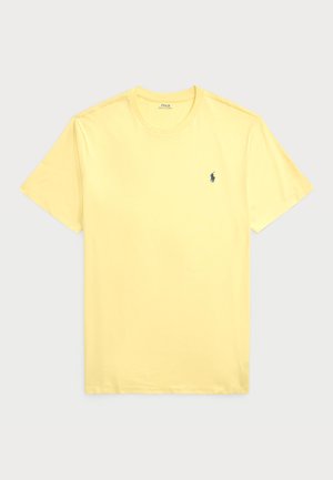 T-shirt en coton jaune à manches courtes, col rond et un petit logo bleu marine sur la poitrine gauche. Texture lisse, sans motifs.