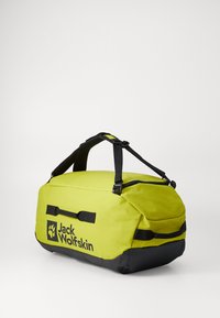 Groene sporttas met zwarte bodem, waterafstotende stof, dubbele handvatten aan de bovenkant, ritssluiting en logo aan de zijkant. Compact en stevig ontwerp.