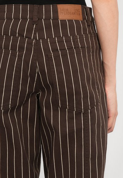Brown striped trousers made of cotton, featuring white vertical stripes, two back pockets, and a leather tag with brand name on the waistband.