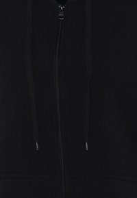 Černá mikina na zip se stahovacími šňůrkami, měkký materiál a kontrastní zip. Jednoduchý design, bez vzorů nebo akcentů.