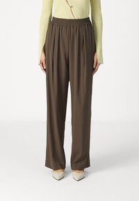 Brune plisserte bukser med elastisk midje, laget av lett stoff, med løs passform og glatt tekstur.