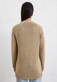 Beige gebreide trui met een losse pasvorm, met een ronde halslijn en geribbelde zoom, van achteren gezien. Textuurstof, lange mouwen.