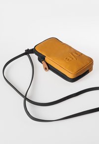 Gelbe Leder-Crossbody-Tasche mit einem schwarzen Reißverschluss und einer Umhängevorrichtung. Die Vorderseite zeigt ein geprägtes Logo. Kompakte rechteckige Form mit glatter Oberfläche.