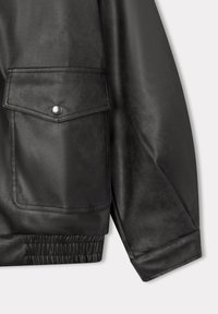 Giacca in ecopelle nera con grande tasca frontale, polsini elastici e texture liscia. Il design include un dettaglio con bottone a pressione.