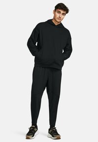 Mustat hupparit, joissa on rento istuvuus, sekä yhteensopivat kapenevat collegehousut, joissa on teksturoitu kangas. Yhdistetty mustiin ja ruskeisiin tennareihin.