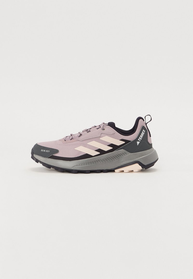 Trail schoenen met een ademende lichtpaarse bovenkant, zwarte accenten en een gestructureerde grijze zool. Voorzien van drie witte strepen en een trekhaan.