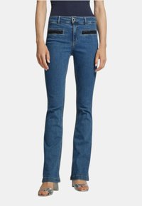 Jeans a zampa d'elefante in denim blu con accenti decorativi in tessuto nero sulle tasche, design a cinque tasche e leggera scoloritura. Dettagli delle cuciture sulle gambe.