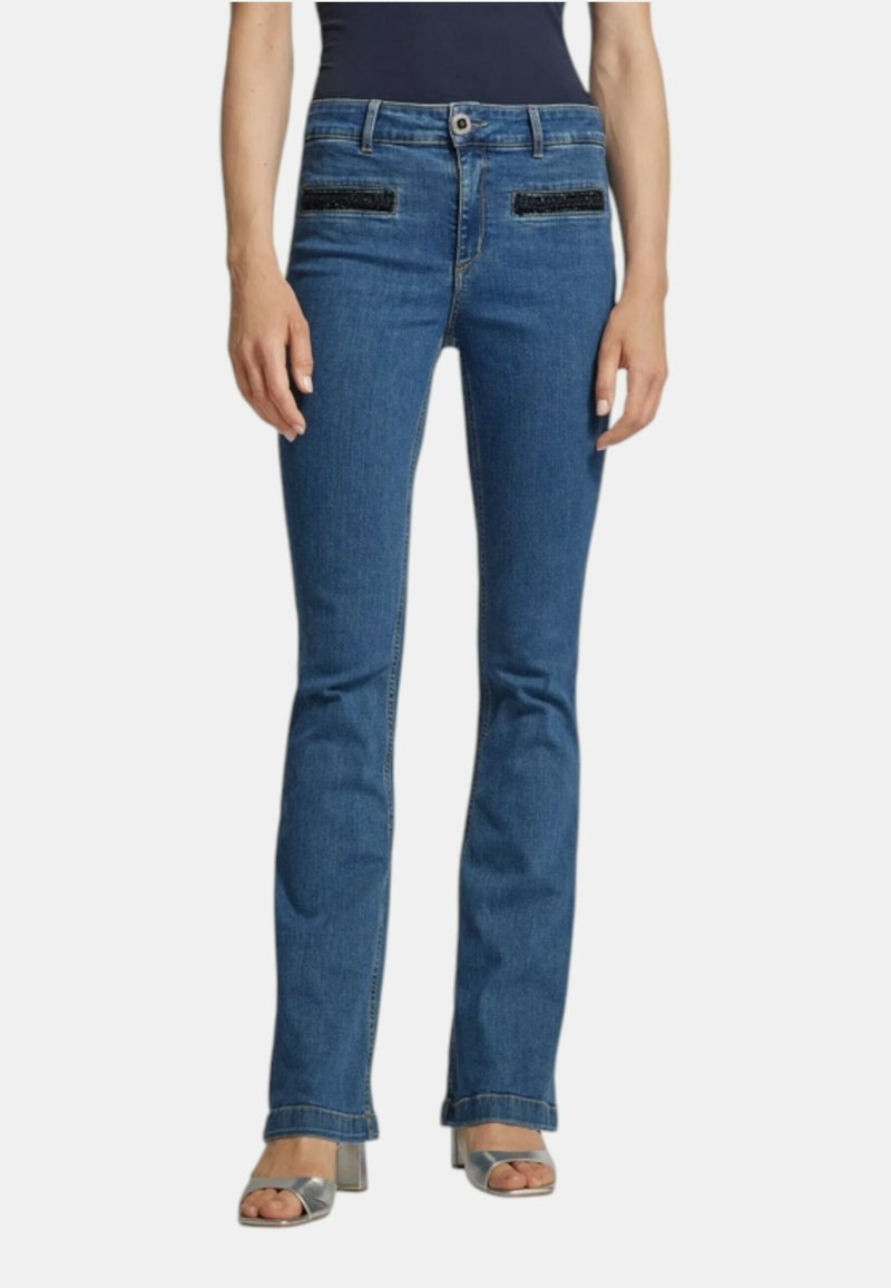 Jeans a zampa d'elefante in denim blu con accenti decorativi in tessuto nero sulle tasche, design a cinque tasche e leggera scoloritura. Dettagli delle cuciture sulle gambe.