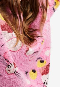 Pull en laine tricoté rose vif avec une texture duveteuse, arborant des motifs d'animaux colorés et des motifs géométriques. Fil doux avec des accents vibrants.