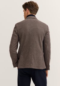 Brauner strukturiert Blazer mit dezentem Karomuster, Einreiher und Spitzrevers. Die Rückseite hat einen Mittelbelüftungsschlitz und eine taillierte Passform.