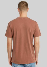 T-shirt di cotone marrone vista da dietro, con maniche corte, un semplice collo rotondo e una vestibilità comoda. Tessuto liscio senza motivi.