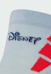 Calcetín azul claro con textura acanalada, que presenta un logo de Disney en azul oscuro y dos formas de diamante rojas. Material de punto suave, diseño de longitud hasta el tobillo.