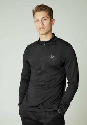 Schwarzes Longsleeve-Shirt mit Viertelreißverschluss und matter Oberfläche, mit einem Berglogo auf der Brust und strukturierten Schulterpaneelen. Glattes Material.