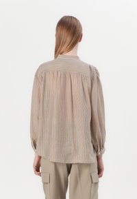 Camisa de manga longa às riscas em tons de bege, laranja e azul, com costas pregueadas, punhos abotoados e colarinho. Tecido suave e leve.