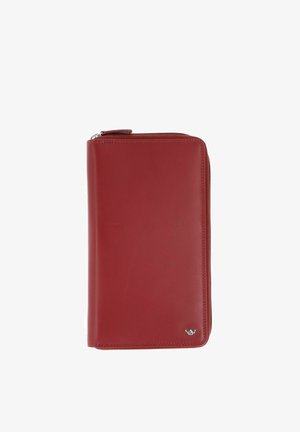 Portefeuille en cuir rouge avec fermeture éclair tout autour et petit emblème argenté dans le coin inférieur droit, photographié sur fond blanc.